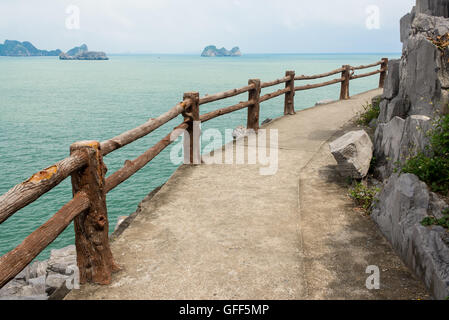 Percorso vuoto con staccionata in legno su una scogliera di fronte al mare aperto con le piccole isole della distanza Foto Stock