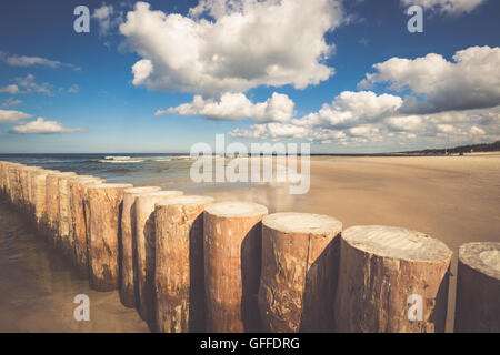 I frangiflutti in legno sulla sabbiosa spiaggia Leba nel tardo pomeriggio, Mar Baltico, Polonia Foto Stock