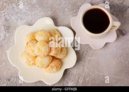 Snack brasiliano Pao de Queijo (formaggio pane) sulla piastra bianca con tazza di caffè sul tavolo di marmo. Messa a fuoco selettiva Foto Stock