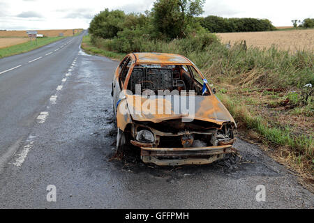 I resti di un bruciato auto (che ha fuso l'asfalto sotto) nel Wiltshire, Regno Unito. Foto Stock