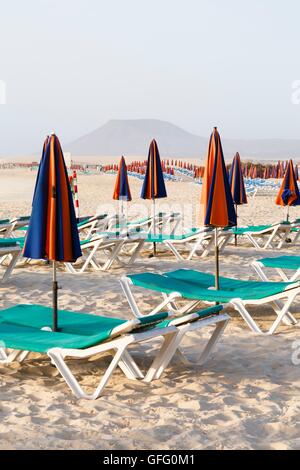 Svuotare le sedie a sdraio e ombrelloni sulla spiaggia Foto Stock