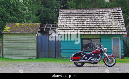 Un motociclo parcheggiato sul ciglio della strada di fronte una colorata capanna rustica in stato di Washington's Highway 2. Foto Stock