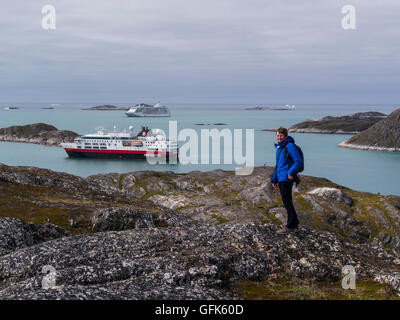 Turista femminile sulla collina sopra la città Paamiut due ormeggiate navi da crociera nel fiordo Kuannersooq Sermersooq comune sulla costa del Mare del Labrador Groenlandia Foto Stock