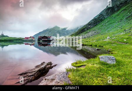 Sunrise a glaciale lago Balea in una mattinata nebbiosa, le montagne dei Carpazi della Romania Foto Stock