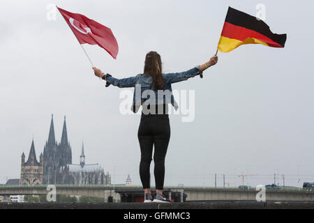 Colonia, Germania. 31 Luglio, 2016. Una giovane donna vola il tedesco e bandiera Turca con la cattedrale di Colonia/Kölner Dom all'indietro. I dimostranti si riuniscono per partecipare alla pro-Erdogan dimostrazione a Deutzer Werft in Colonia. Credito: Bettina Strenske/Alamy Live News Foto Stock