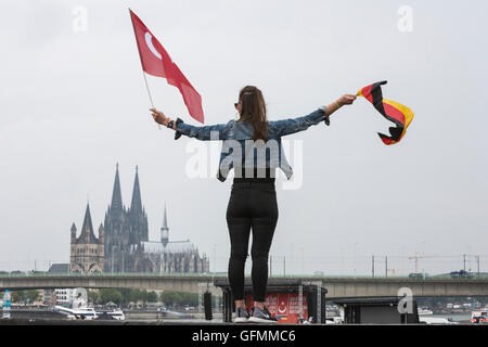 Colonia, Germania. 31 Luglio, 2016. Una giovane donna vola il tedesco e bandiera Turca con la cattedrale di Colonia/Kölner Dom all'indietro. I dimostranti si riuniscono per partecipare alla pro-Erdogan dimostrazione a Deutzer Werft in Colonia. Credito: Bettina Strenske/Alamy Live News Foto Stock