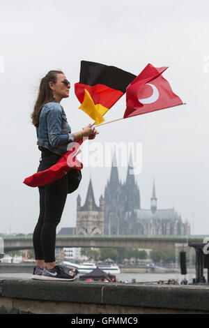 Colonia, Germania. 31 Luglio, 2016. Una giovane donna vola il tedesco e il turco e tedesco bandiere con la cattedrale di Colonia/Kölner Dom all'indietro. I dimostranti si riuniscono per partecipare alla pro-Erdogan dimostrazione a Deutzer Werft in Colonia. Credito: Bettina Strenske/Alamy Live News Foto Stock