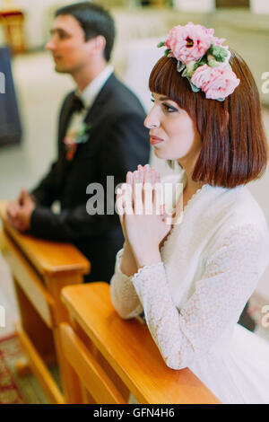 Sposa e lo sposo la preparazione per la comunione sulle ginocchia a cerimonia di matrimonio in chiesa Foto Stock