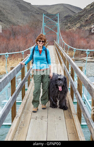 Donna e cane di Terranova sulla sospensione ponte sopra il fiume Yakima a Umtanum Foto Stock