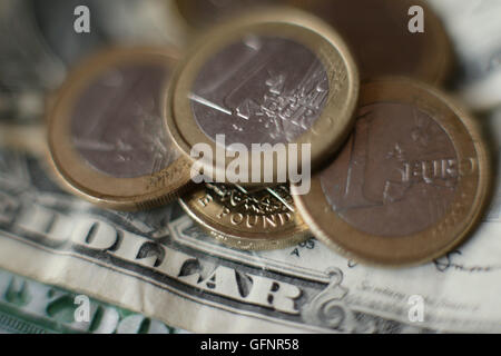 Uno britannico pound coin al di sotto di una pila di 1 monete in euro, sulla sommità di una di noi un dollaro, a Londra. Foto Stock
