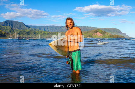 Surfer in Hanalei Bay su Kauai, con Mt. Makana, chiamato Bali Hai, in distanza Foto Stock