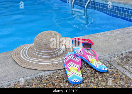 Una donna con cappello di occhiali da sole e flip-flop da piscina. Foto Stock