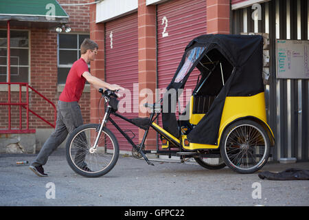 Noleggio taxi driver che fissa il suo veicolo, sale come City, Stati Uniti d'America Foto Stock