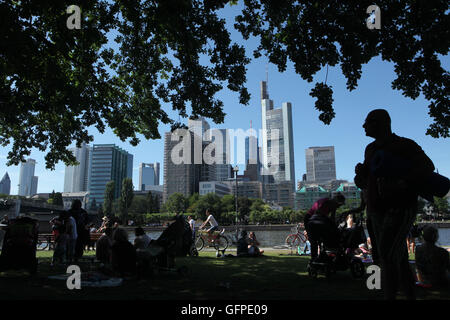 Le persone godono di estate sul terrapieno Schaumainkai in Frankfurt am Main, Hesse, Germania, con moderni grattacieli del Bankenviertel (distretto bancario) sorto in background. Foto Stock