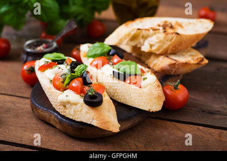 Bruschetta con pomodori, mozzarella, olive e pesto di basilico Foto Stock