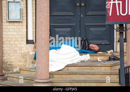Senzatetto uomo dorme in modo irregolare a porta a Bournemouth in luglio Foto Stock