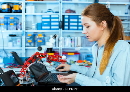 Schoolgirl regola il braccio di robot modello, ragazza in un laboratorio di robotica Foto Stock