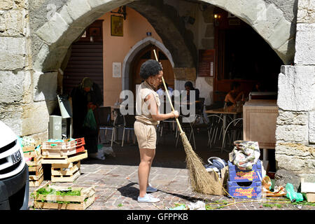 Donna mercato titolare di stallo di spazzamento stradale pulizia eliminazione rifiuti rifiuti a Annecy in Francia Foto Stock