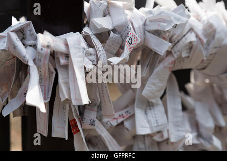 Small paper sheets with personal prayers and memories attached to a metal grid in front of a Shinto temple in Tokyo japan Foto Stock