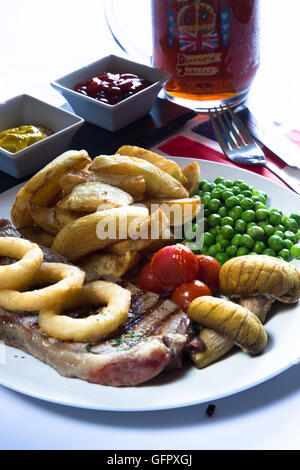 Un tradizionale pub inglese/bar piatto di carne bovina britannica Scamone bistecca con patatine/patatine fritte e verdure e condimenti. Foto Stock