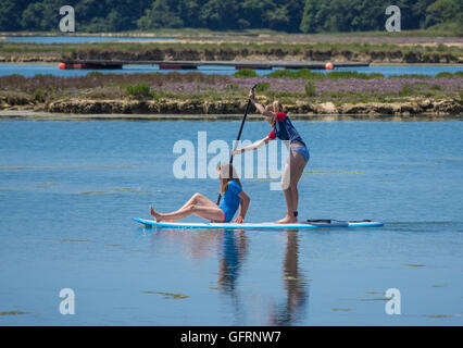 Due ragazze godendo di stand up paddle imbarco in Newtown River sull'Isola di Wight, Regno Unito Foto Stock