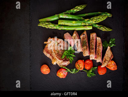 Succosa bistecca mezzo raro di manzo con spezie e pomodori, asparagi. Vista superiore Foto Stock