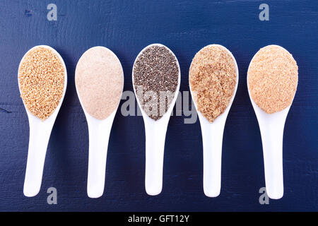 Granuli compresi, grano bianco quinoa, psillio lolla di polvere nera, Chia, il germe di grano e la massa LSA mix, in bianco misurino Foto Stock