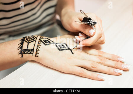 Il processo di applicazione della Mehndi sulla mano femmina close up Foto Stock