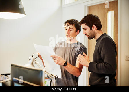 Un workshop di mobili ,due persone per discutere un progetto facendo riferimento ai disegni e computer laptop Foto Stock