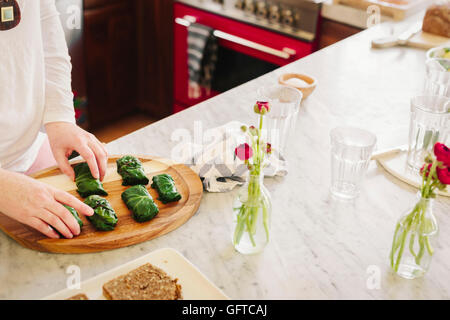 Una donna che prepara le foglie di vite ripiene come un piatto del pranzo in una cucina Foto Stock