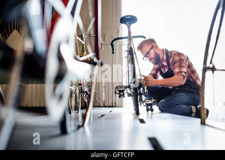 Un uomo che lavora in un negozio di riparazione di biciclette Foto Stock