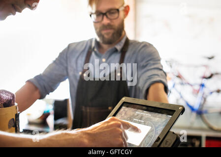 Un uomo in un negozio di riparazione di biciclette usando un computer portatile che esegue un business Foto Stock