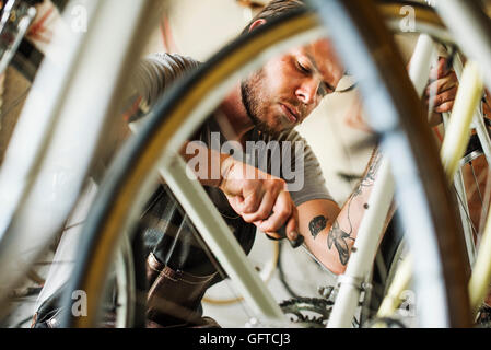Un uomo che lavora in un negozio di riparazione di biciclette Foto Stock