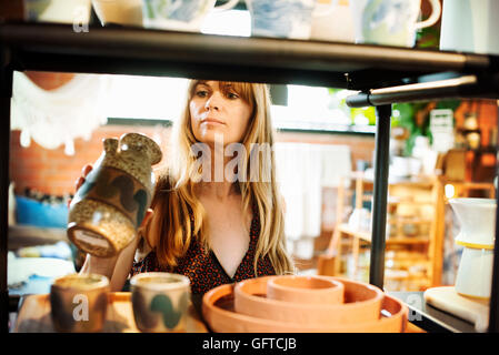 Donna in piedi in un negozio tenendo un piccolo vaso in ceramica Foto Stock