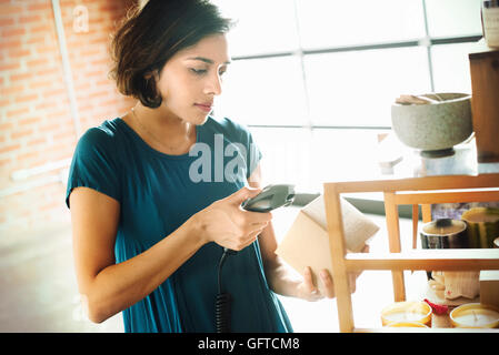 Giovane donna in un negozio la scansione del codice a barre di un vaso di ceramica con uno scanner di codici a barre Foto Stock