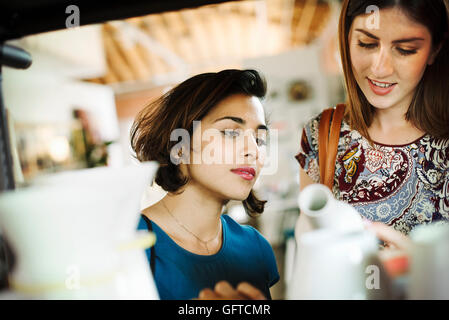 Due giovani donne in un negozio in cerca di un vaso in ceramica bianca Foto Stock