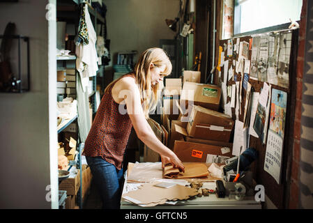 Donna con capelli lunghi biondi in piedi nel magazzino di un negozio di merchandising di incarto in carta marrone Foto Stock