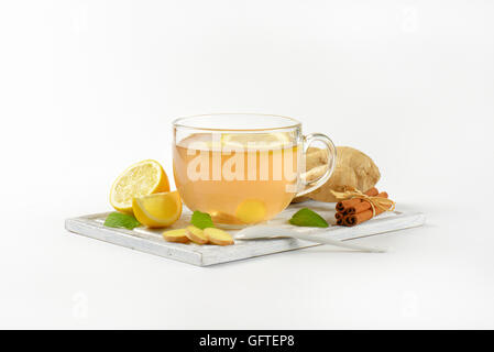 Tazza di tè allo zenzero con succo di limone, lo zenzero fresco e cannella sul tagliere di legno Foto Stock