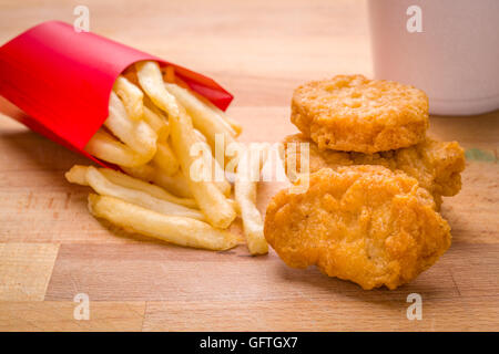 Bambini Bambino pasto golden brown pepite di pollo e patatine fritte su un sfondo di legno Foto Stock