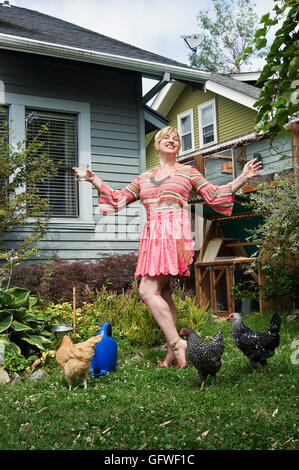 Un ritratto di una donna di Portland in piedi nel suo cortile interno con il suo piccolo gregge dei polli che utilizza per la deposizione delle uova. chic Foto Stock