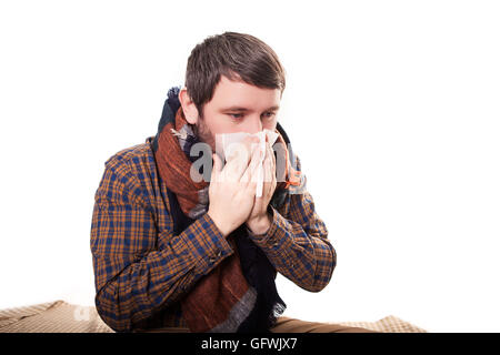 Uomo con un fazzoletto in mano, salviette per le mani il suo naso, gli occhi dei pazienti e brillare uomo su uno sfondo luminoso vicino fino a guardare verso la telecamera.un ragazzo con un naso che cola. La cura della salute per le persone Foto Stock