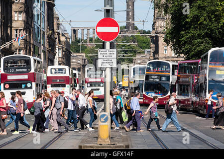 Vista dei pedoni che attraversano via e molti autobus pubica su Princes Street di Edimburgo , in Scozia, Regno Unito Foto Stock