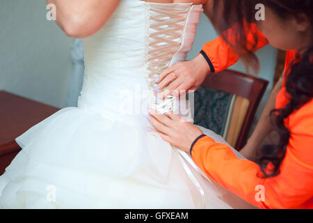 Aiutare la sposa a mettere il suo abito da sposa a Foto Stock