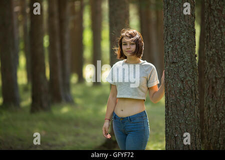 Teen girl in piedi nel bosco in prossimità di un albero. Foto Stock