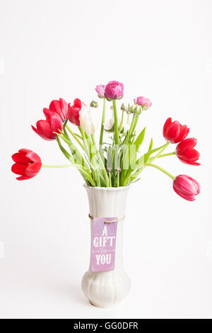 White vaso con tulipani rossi e la carta regalo Foto Stock