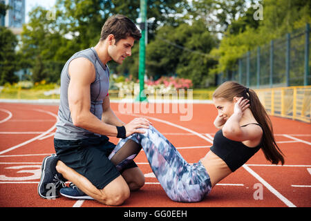 Giovane bella giovane facendo esercizi sportivi allo stadio Foto Stock