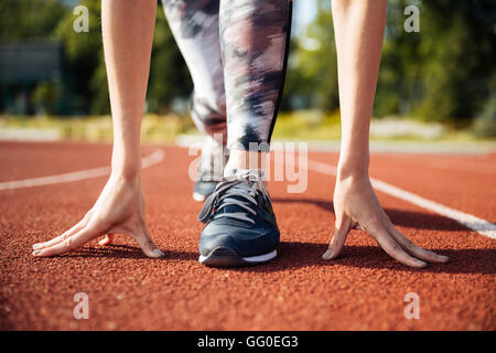 Immagine ritagliata di una femmina di sprinter ottenere pronto per essere avviato allo stadio Foto Stock