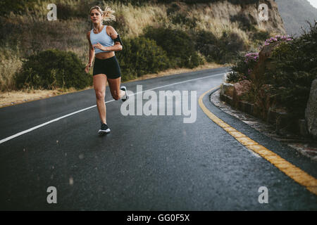 A piena lunghezza shot della giovane donna fitness all'aperto in esecuzione su una strada aperta in campagna. Foto Stock