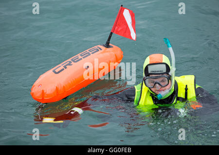 Scuba Diver in colorato fluorescente in marcia mare azienda Cressi siluro galleggiante a Swanage in luglio Foto Stock