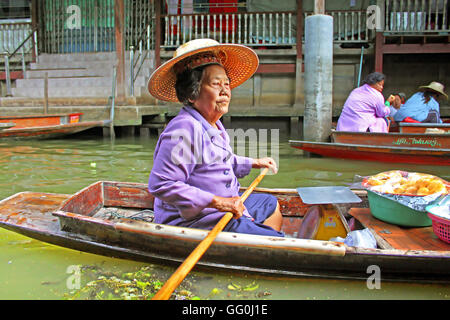 KANCHANABURI, Tailandia - 11 giugno 2014: donna non identificato è vele nel mercato galleggiante lungo case zattera sul fiume Kwai Foto Stock